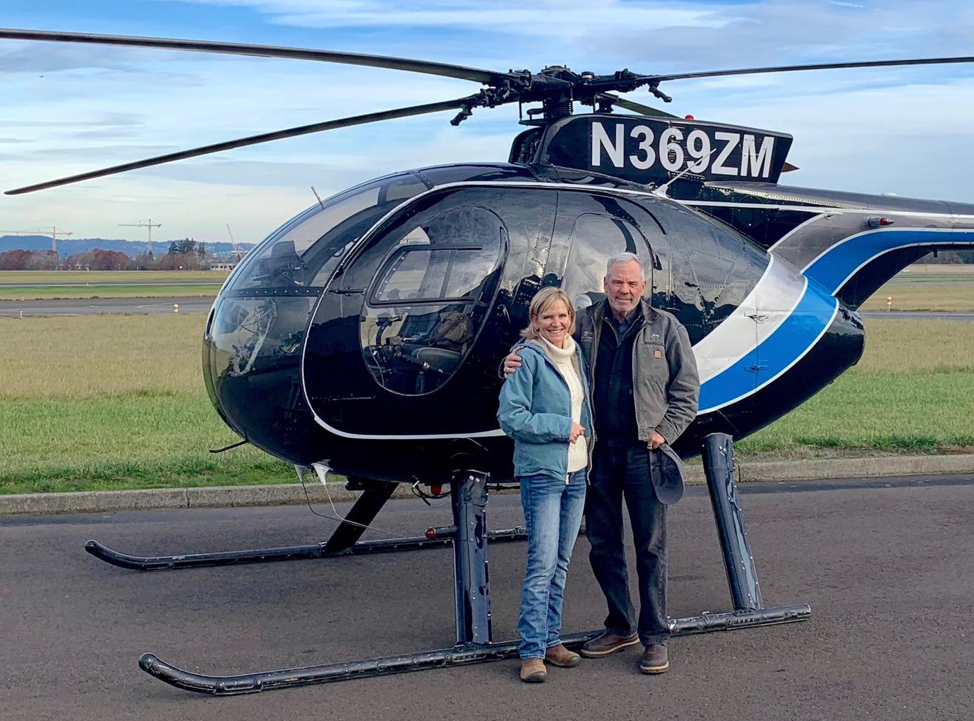 Jerry and Alison Trimble in front of an MD-500 helicopter